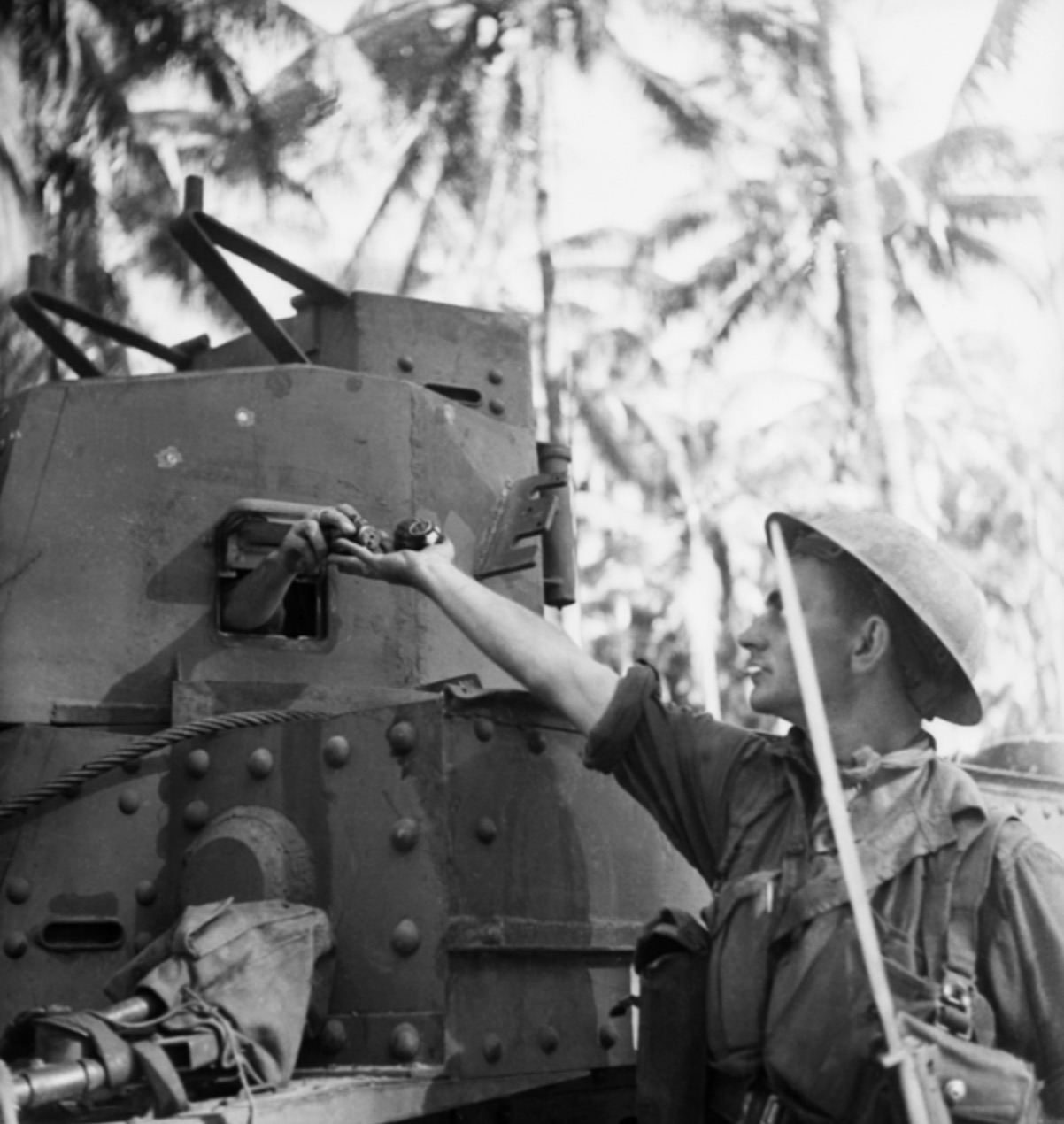 An infantryman receives grenades from the crew of a tank during an attack at Buna. 